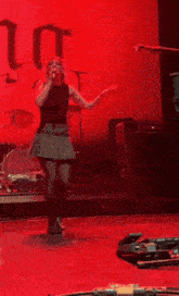 a woman sings into a microphone on a stage in front of a drum set that says always