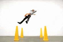 a man is jumping over a set of yellow traffic cones