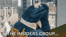 a cookie monster is sitting in front of a window with the words `` the insiders group ... '' written on it .