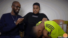 a man wearing a black puma sweatshirt sits next to another man