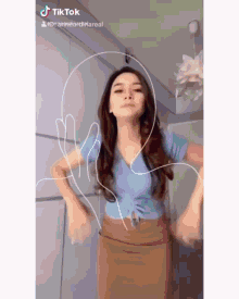 a woman wearing a blue top and a brown skirt is dancing on tiktok