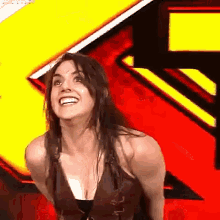 a woman is smiling and standing in front of a yellow and red background .