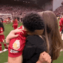 a woman is hugging a man in a red shirt that says no room for men .