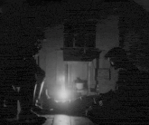 a black and white photo of two men sitting in a dark room with the caption what