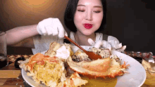 a woman is eating a large crab with a spoon .