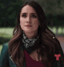 a woman wearing a bandana and a green jacket with a red t in the corner