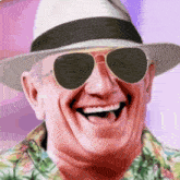 a man wearing a hat and sunglasses laughs with his mouth open