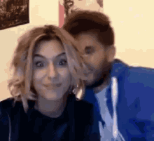 a man is kissing a woman on the cheek while she looks at the camera .