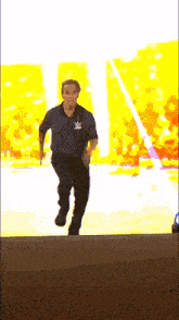 a man in a blue shirt with a w logo on his chest is running