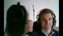 a man wearing headphones holds up a gun in front of his face