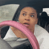 a woman with a pink steering wheel looks surprised