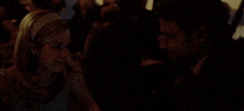 a man and woman looking at each other in a dark room