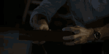 a man wearing a watch and a ring is opening a box