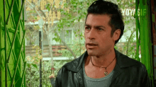 a man in a black leather jacket looks out a window with yoy gif written on the bottom