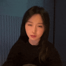 a woman with long black hair looks at the camera