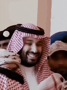 a man with a beard wearing a head scarf and hat smiles