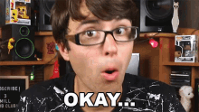 a man wearing glasses says " okay " in front of a speaker