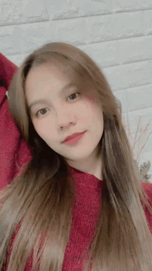 a woman with long brown hair is wearing a red sweater and red lipstick