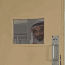 a man looks out of a door with arabic writing