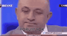 a man in a suit and tie is sitting in front of a blue screen with his eyes closed and the words yorum yok on it .
