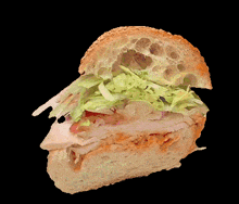 a sandwich with lettuce and meat on a sesame seed bun on a black background
