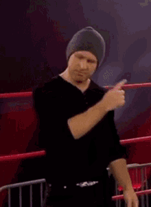 a man wearing a beanie and a black shirt is standing in a ring with his eyes closed