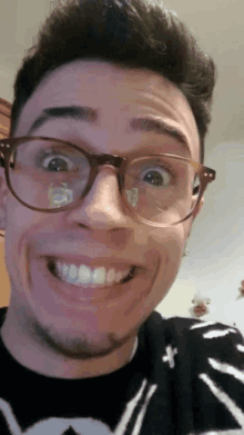 a man wearing glasses and a sweater with a cross on it