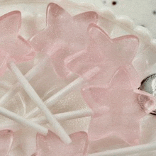 a close up of a plate of pink star shaped lollipops .