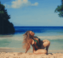 a woman in a bikini is laying on her back on the beach