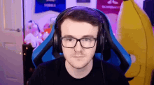 a man wearing glasses and headphones is sitting in a chair in front of a banana mascot .