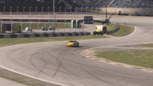 a yellow race car is going around a curve on a race track