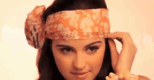 a woman wearing a headband and a pearl bracelet looks at the camera