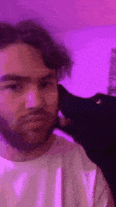 a man with a beard is being kissed by a black dog on the cheek .