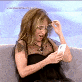 a woman sitting on a couch looking at a cell phone with the hashtag loestamos consiguiendo