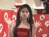 a woman in a red dress stands in front of a wall with letters a and g on it