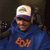a man wearing headphones and a lakers hat is holding a green necklace