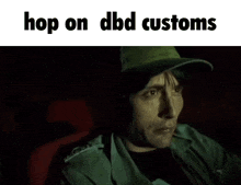 a man wearing a green hat is sitting in a dark room with the words hop on dbd customs above him