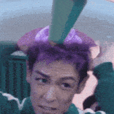 a man with purple hair is wearing a green and white shirt