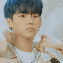 a young man with blue hair and earrings is being adjusted by a woman .