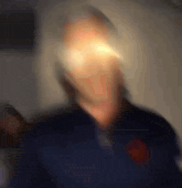 a blurry image of a man 's face with a red emblem on his chest