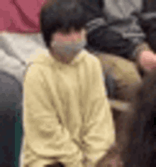 a person wearing a mask is sitting in a chair in a crowd .