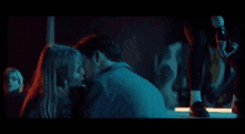 a man and a woman are kissing in front of a sign that says o t