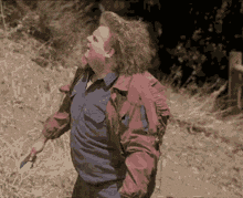 a man in a blue shirt and a red jacket is holding a knife