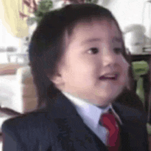 a close up of a baby wearing a suit and tie .