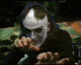 a painting of a man with white paint on his face reaching out his hands