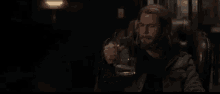 a man with a beard is holding a glass of beer in his hand