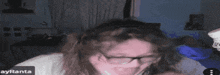 a woman wearing glasses is looking at the camera while holding a skull .