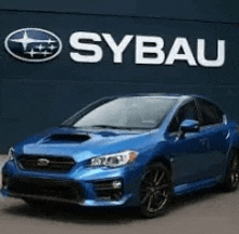 a blue subaru wrx sti is parked in front of a subaru dealership sign .