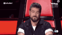 a man with a beard is sitting in a chair with his eyes closed in front of a screen that says lavozkids1
