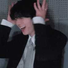 a man in a suit and tie is laughing while holding his head .